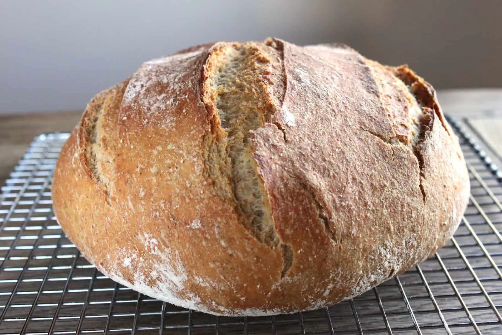Freshly baked artisan bread loaf cooling on a wire rack with a golden crust.