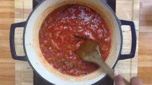Red tomato sauce cooking in a pot, stirred with a wooden spoon, perfect for pasta dishes.