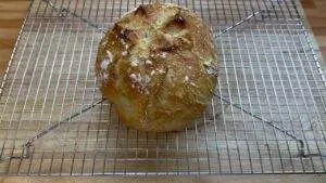 Freshly baked rustic bread cools on a wire rack in the kitchen.