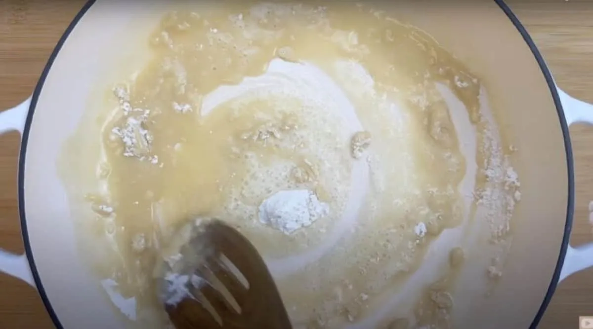 Stirring flour and butter in a pan to make roux for sauce preparation.