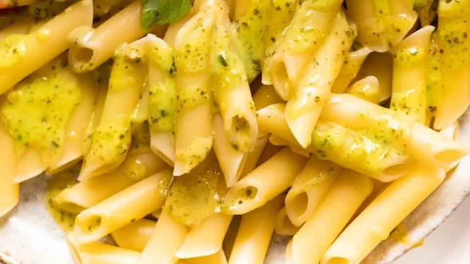 Penne pasta with creamy pesto sauce on a plate.