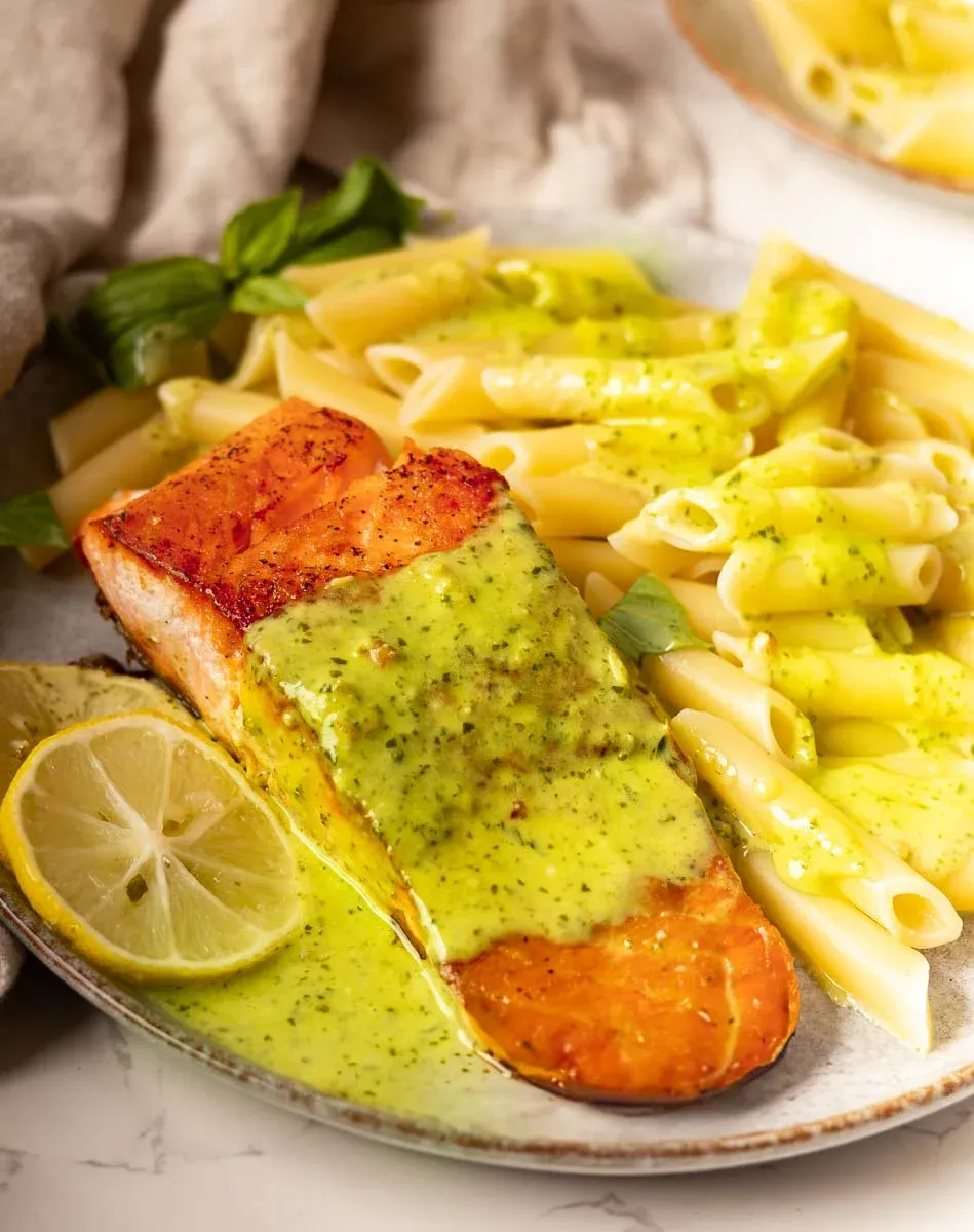 Salmon and Pesto Pasta with basil leaves.