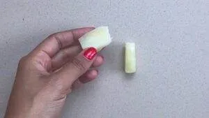 Hand holding aloe vera slice on a beige background, showcasing natural skincare ingredient.