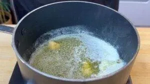 Butter melting in a pot on a stovetop, creating bubbles and foam, ideal for baking or cooking recipes.