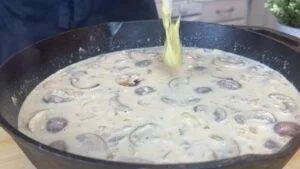 Creamy mushroom sauce simmering in a cast iron skillet for a delicious homemade recipe.