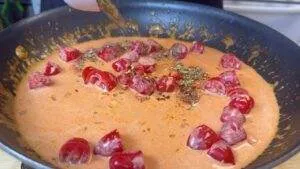 Creamy tomato sauce with cherry tomatoes and spices cooking in a pan.