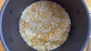 Rice and shredded carrots being cooked in a pot for a healthy dish preparation.