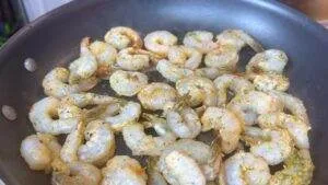 Seasoned shrimp sizzling in a pan, ready to be cooked to perfection. Delicious seafood dish in preparation.