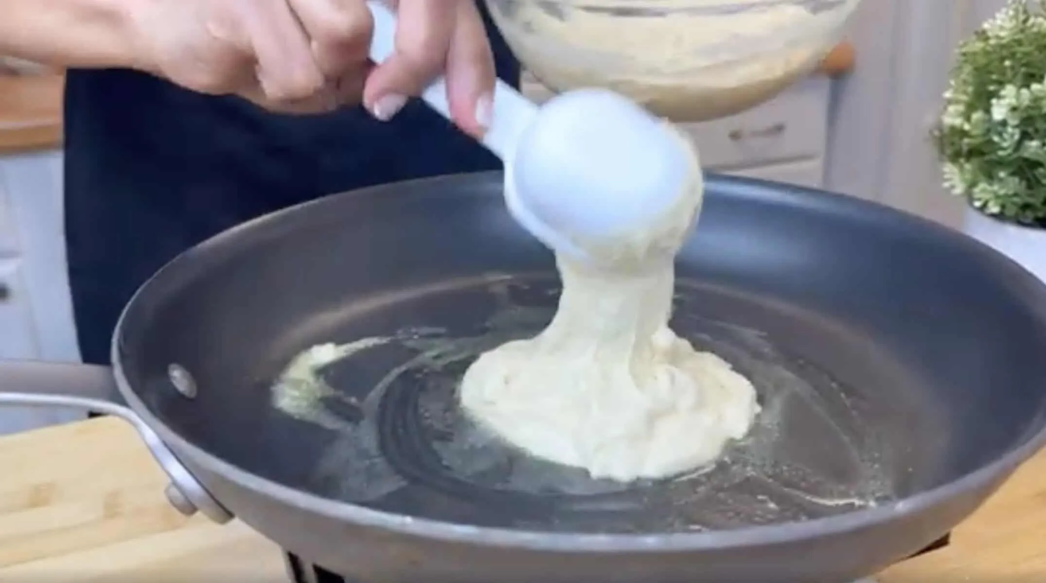 Pouring pancake batter into a hot nonstick pan for cooking, close-up view.