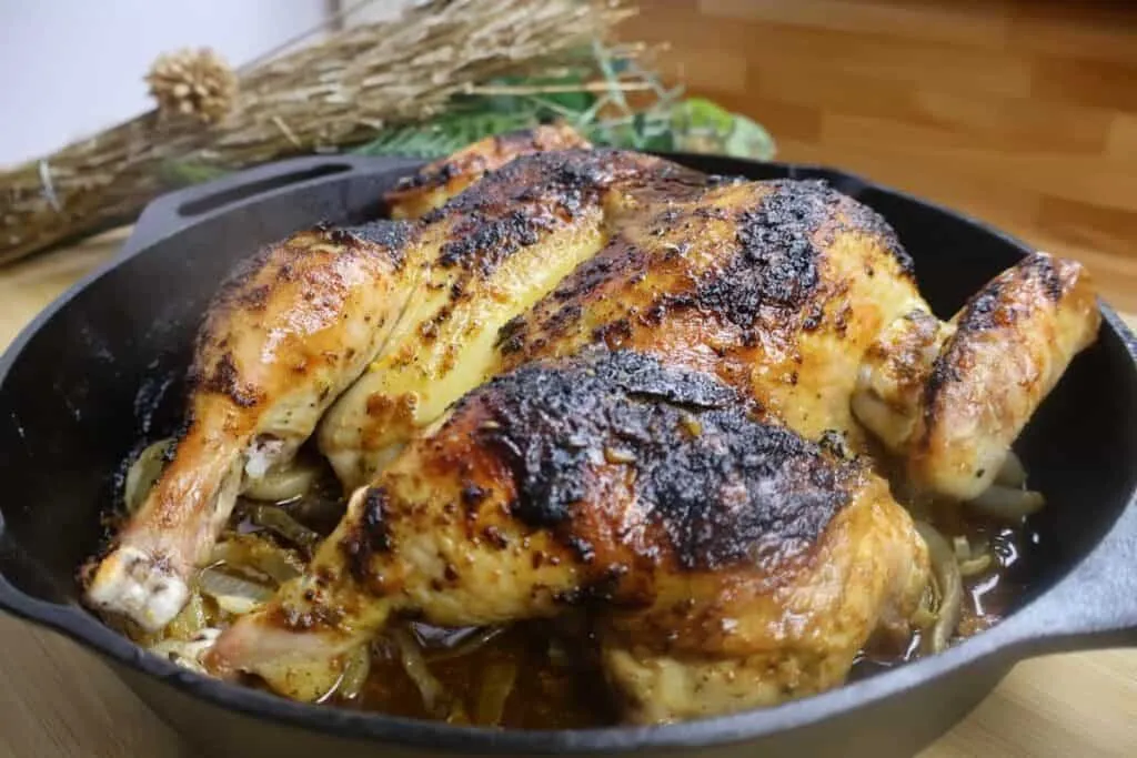Roasted chicken in a cast iron skillet with crispy skin, seasoned to perfection. Ideal for a savory homemade meal.
