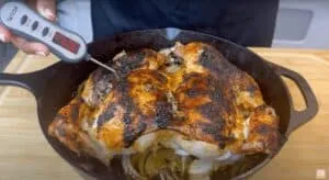 Roasted chicken in cast iron skillet with thermometer reading 169°F, perfect for a delicious, savory dinner.