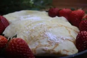 Delicious crepes dusted with powdered sugar, surrounded by fresh strawberries. Perfect breakfast or dessert treat.