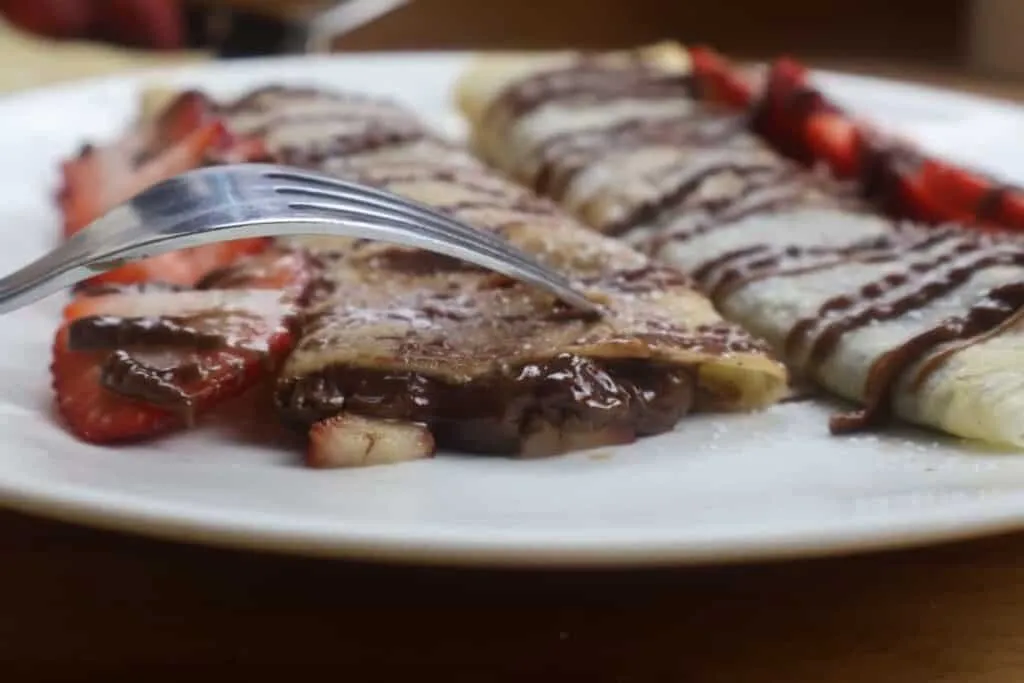 Delicious Banana & Strawberry Crepes drizzled with chocolate, filled with strawberries and bananas.