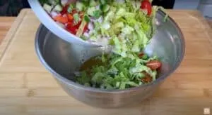 Fresh salad ingredients being poured into a mixing bowl for a healthy, colorful meal preparation.