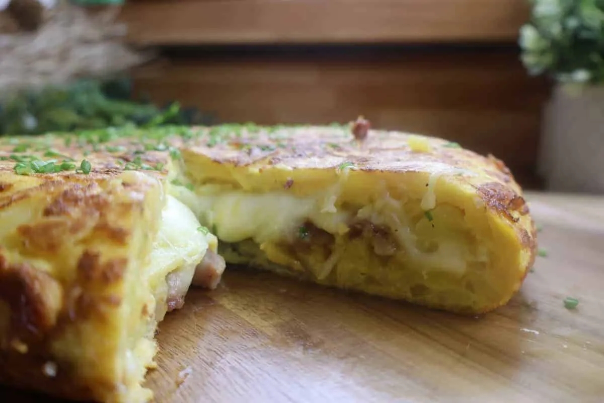 Cheesy stuffed potato omelette garnished with herbs on a wooden board, perfect for breakfast or brunch inspiration.