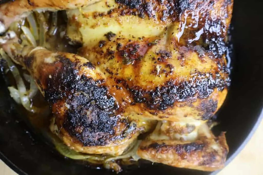 Roasted chicken with crispy skin in a cast iron skillet. Juicy and perfectly seasoned for a delicious meal.
