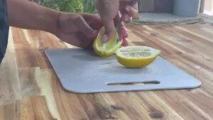 Slicing a lemon on a cutting board in a kitchen setting for fresh juice or cooking preparation.