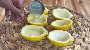 Pouring lemon mousse into lemon halves on a woven placemat, creating a refreshing citrus dessert.