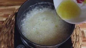 Pouring melted butter into boiling pan mix on stovetop for a cooking recipe.