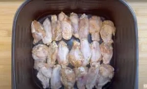 Raw marinated chicken wings in an air fryer tray, ready for cooking.