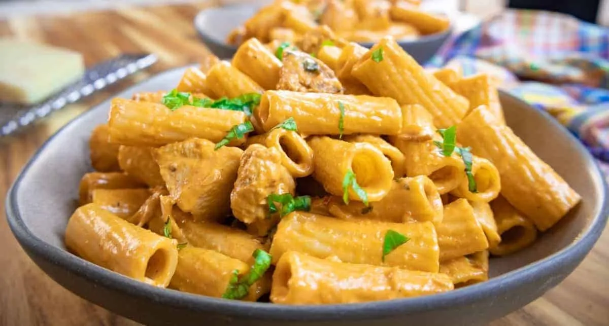 Creamy rigatoni pasta with fresh parsley and tender chicken, served in a bowl for a delicious, comforting meal.