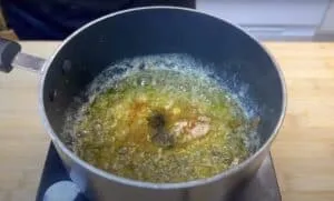 Pot of sizzling butter with spices on a stovetop, ready for cooking aromatic dishes.