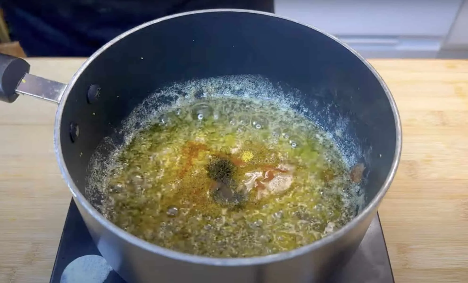 Pot of sizzling butter with spices on a stovetop, ready for cooking aromatic dishes.