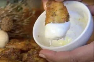 Chicken wing dipped in creamy ranch sauce, perfect appetizer for game day or gatherings.