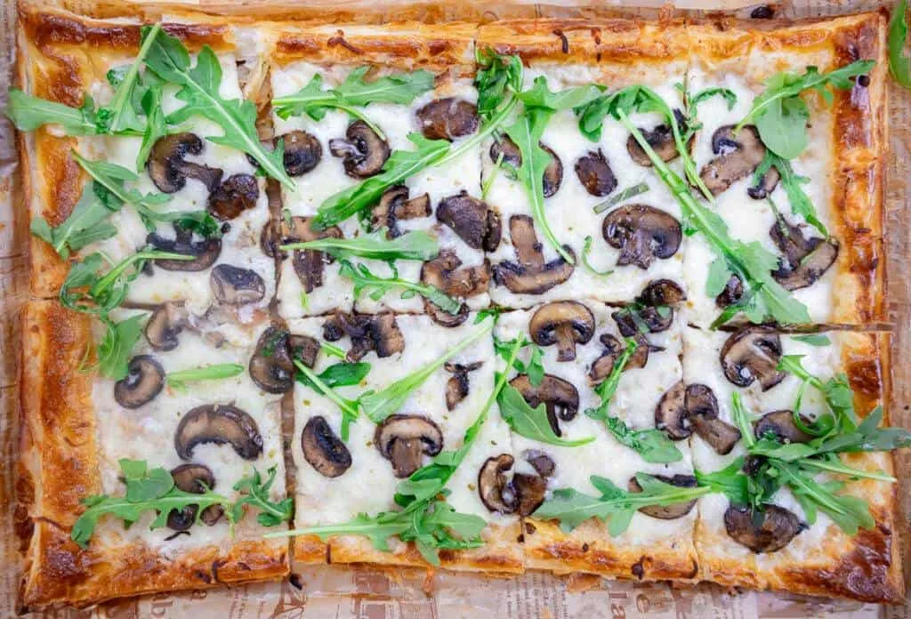 Sliced Mushroom & White Sauce Puff Pastry Pizza on crispy crust with melted cheese.