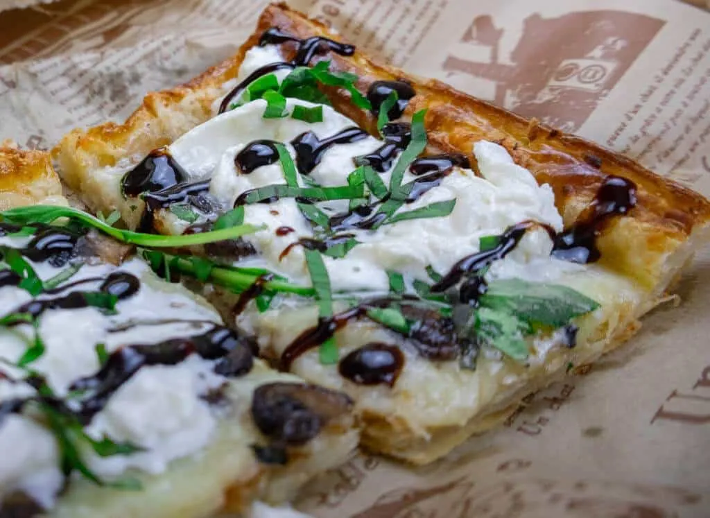 Gourmet pizza slice topped with mozzarella, balsamic glaze, fresh greens on crispy crust. Ideal for pizza lovers.