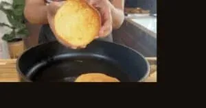 Close-up of a toasted burger bun held over a skillet, ready for sandwich preparation.
