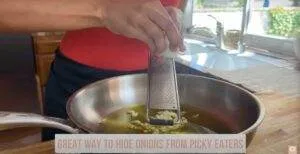 Grating onion into a pan; a clever cooking tip to disguise ingredients for picky eaters.