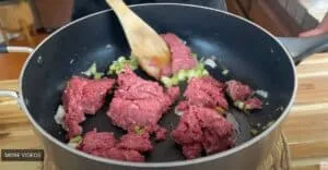 Cooking ground beef with onions and green peppers in a skillet.