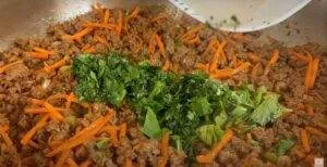 Ground beef with carrots and fresh herbs in a pan, perfect for tasty homemade tacos or a flavorful dinner base.