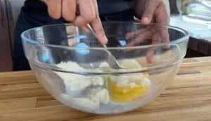 Mixing ingredients in a glass bowl for baking. Step-by-step recipe preparation on a wooden kitchen counter.