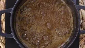 Boiling caramel in a black pot, creating a rich and bubbly texture for a delicious dessert topping.
