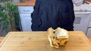 Empty tortilla bowl on a wooden cutting board in a kitchen, ready for filling.