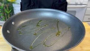 Non-stick frying pan with olive oil drizzled, ready for cooking.
