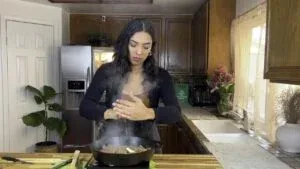 Woman cooking in kitchen, adding butter and lime to a beef fajita dish.