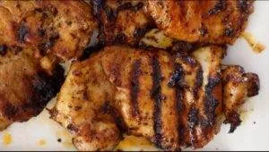 Grilled chicken thighs with savory char marks on a white plate, perfect for a delicious meal.