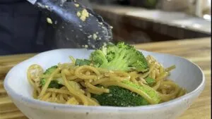 Warm spaghetti with fresh broccoli, tofu and green onions served in a bowl.