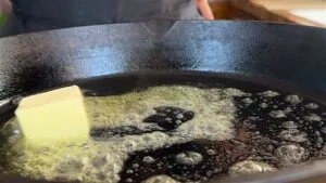 Butter melting in a hot skillet, creating bubbles and sizzling for a delicious cooking start.