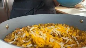 Cheesy beef macaroni in skillet, topped with melted cheddar, ready to serve.