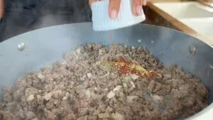 Cooking ground beef with onions and spices in a skillet, adding flavor for a delicious meal preparation.