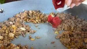 Cooking ground beef and onions in a pan with added tomato paste for a savory dish.