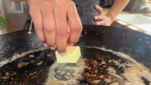 Person melting butter in a hot skillet on a stovetop.