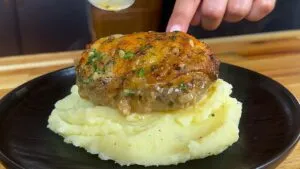 Delicious baked chicken on mashed potatoes with herb garnish.