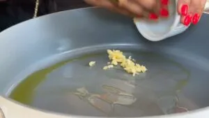 Adding minced garlic to a pan with olive oil. Perfect start for a flavorful dish.