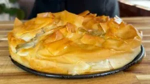 Golden-brown homemade pie with flaky layers on a kitchen countertop, perfect for a delicious meal.