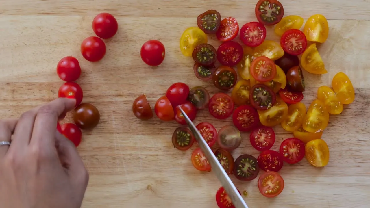 Slicing colorful cherry tomatoes on a wooden board. Fresh ingredients for a tasty meal.